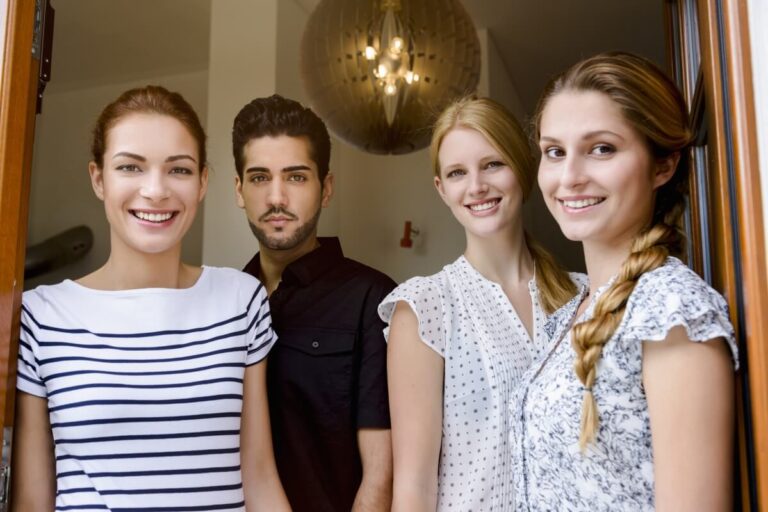 Grupa młodych osób uśmiecha się w drzwiach, symbolizując wspólne zainteresowanie tematem prawo rodzinne.